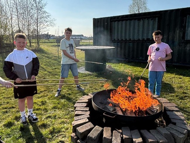 Kinderen steken fikkie bij kampvuur tijdens kinderfeestje bij Recreatieboerderij De Kleine Biesbosch
