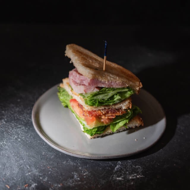 club sandwich met sla en ham op een wit bord
