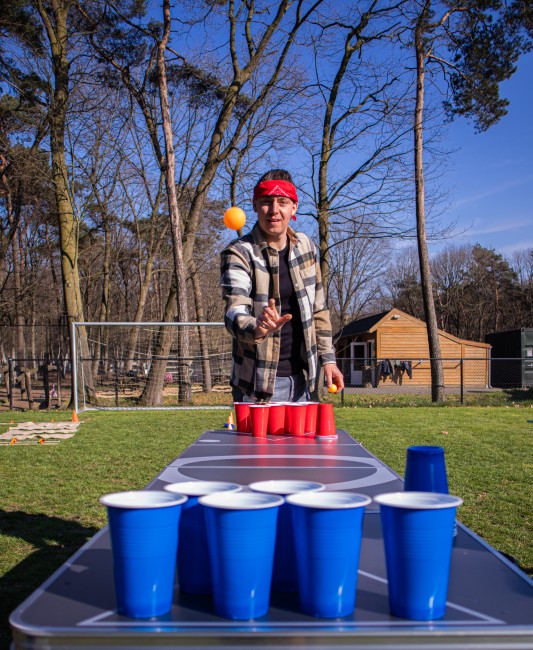 buiten bierpong spel met bekers op tafel en speler die gooit