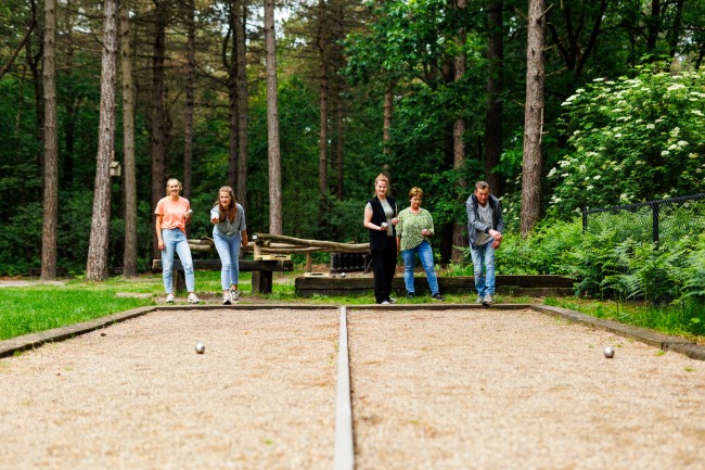 groep speelt jeu de boules in het bos op een zandbaan