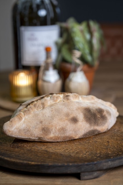 ambachtelijke calzone op houten plank klaar om geserveerd te worden
