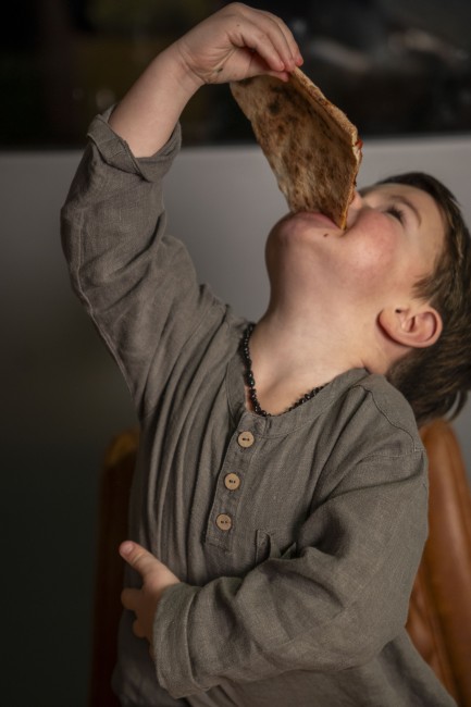 kind eet met enthousiasme een grote punt pizza