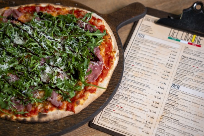 verse pizza met prosciutto en rucola naast het menu van del limone