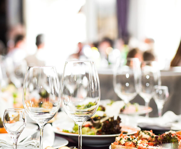 Sparkling glassware stands on long table prepared for wedding di