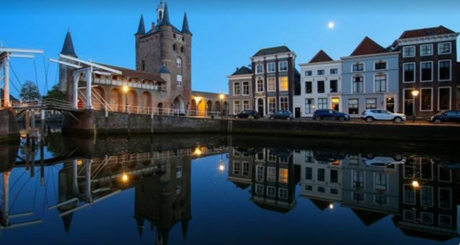 Avondbeeld van de Zuidhavenpoort in Zierikzee met straatverlichting die weerspiegelt in het water
