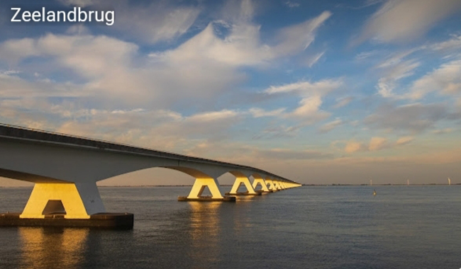 De lange Zeelandbrug die over het kalme water van de Oosterschelde strekt tijdens zonsondergang
