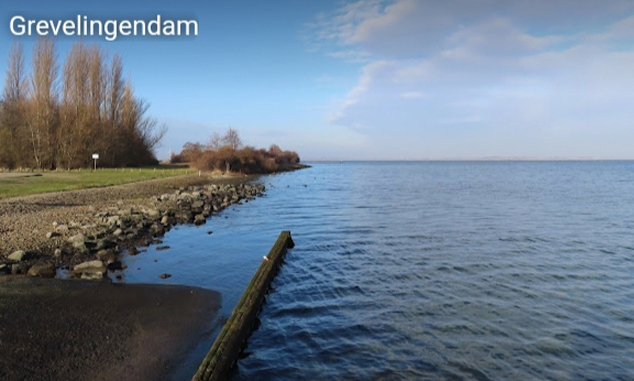 De rustige kustlijn bij de Grevelingendam met helder water en een blauwe lucht, een vredig tafereel in Zeeland