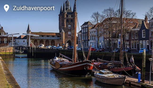 Historische rode zeilboten aangemeerd bij de Zuidhavenpoort in Zierikzee onder een heldere hemel