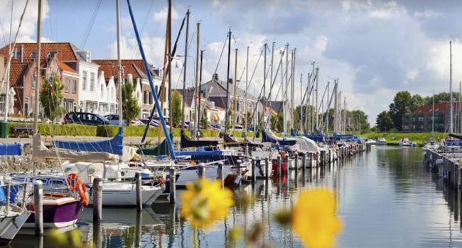 Jachthaven met aangemeerde zeilboten en woonhuizen op de achtergrond in Brouwershaven, Zeeland