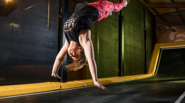 Jonge vrouw maakt een backflip op een trampoline bij FunZone Breda