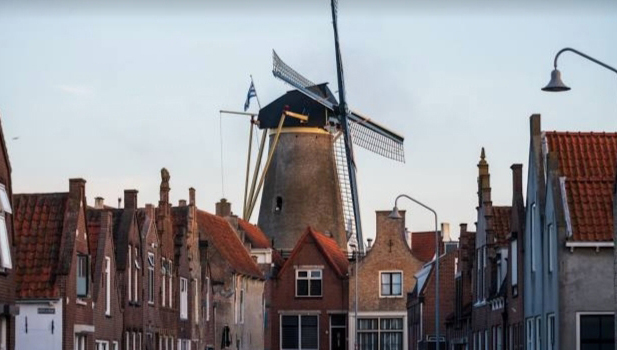 Karakteristieke Nederlandse windmolen torent uit boven de historische huisjes van Zierikzee bij schemering