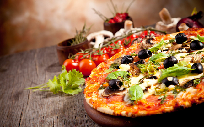 Pizza belegd met groenten en verse kruiden, gepresenteerd op een rustieke houten tafel bij La Pergola.