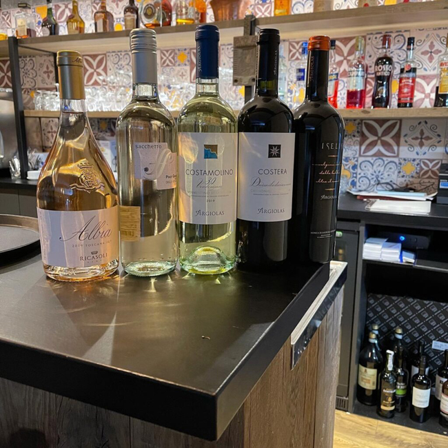 Selectie van witte en rode wijnflessen uitgestald aan de bar van La Pergola.