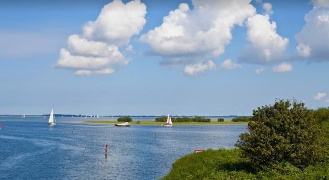Zeilschepen op het kalme water van het Grevelingenmeer met een heldere hemel boven Brouwershaven, Zeeland