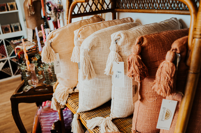 Decoratieve kussens met kwastjes op een rotan bank in de winkel van Liefs Lies in Breskens