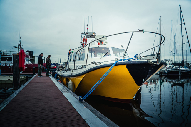 Gele en zwarte boot van Sharky Charters aangemeerd aan de kade in Vrouwenpolder