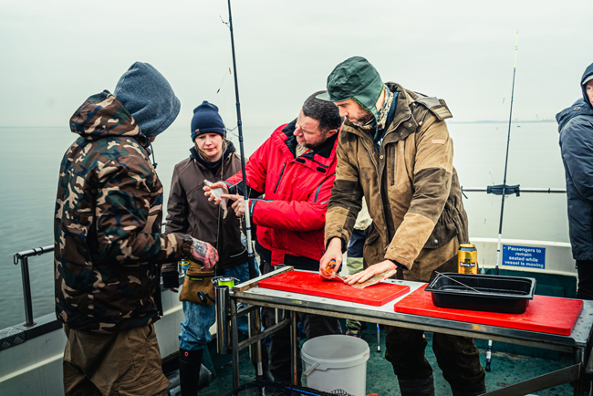 Groep mensen aan het vissen met Sharky Charters, schoonmaken van vis op dek in Vrouwenpolder