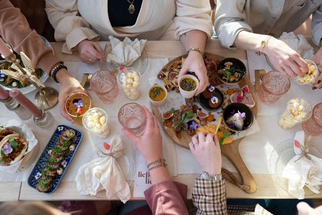 Groep mensen genieten van een gedeelde lunch met diverse gerechten op een tafel bij Liefs Lies in Breskens