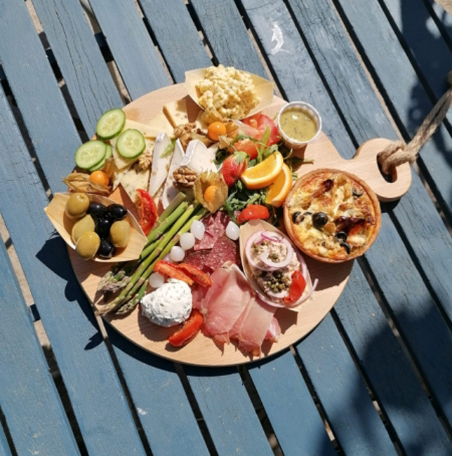 Houten serveerplank met een assortiment van tapas en snacks op een buitentafel bij Herberg Buitenman in Lage Mierde