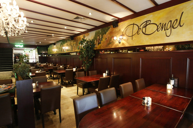 Interieur van restaurant De Bengel met bruine leren stoelen en een muurschildering in Eersel