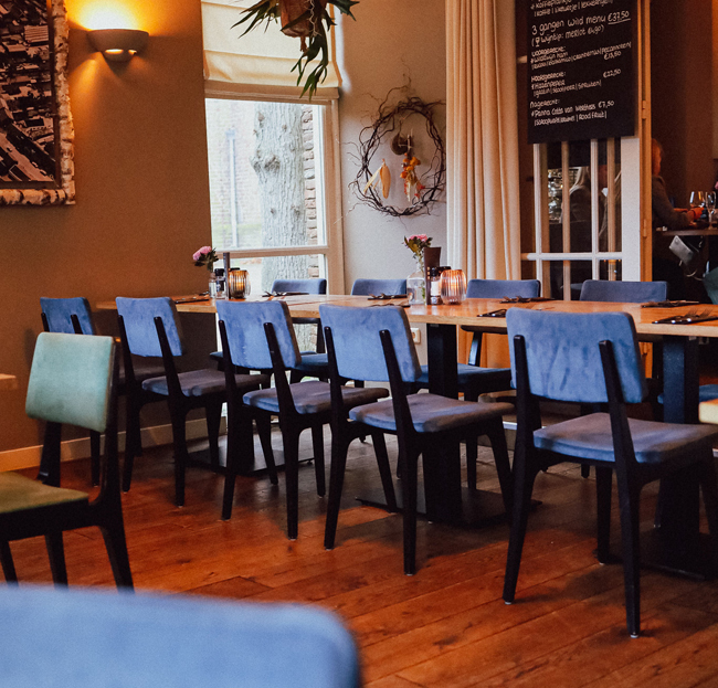 Sfeervol ingerichte eetzaal met blauwe stoelen bij Restaurant Bij Wout in Moergestel