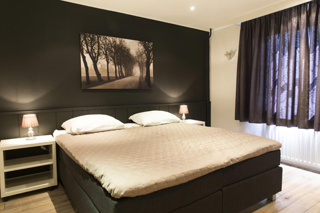 Slaapkamer met groot tweepersoonsbed en sfeerverlichting in Hotel Den Engel in Baarle Nassau