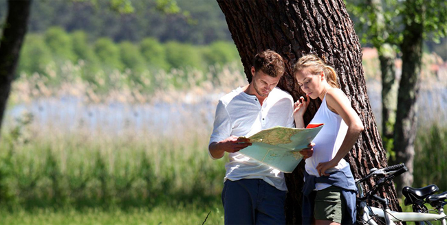 Twee personen die samen een kaart bekijken bij een boom met geparkeerde fietsen in de buurt in Eersel