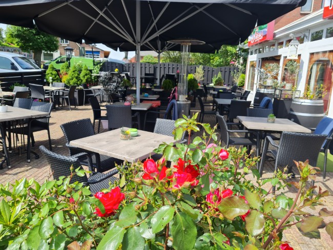 buitenplaats van pizzeria en grill la bella borger met kleurrijke bloemen en uitnodigende zitplaatsen