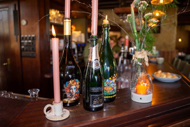 Selectie van bijzondere flessen en kaarslicht op bar bij De Regentenhoeve Biest Houtakker