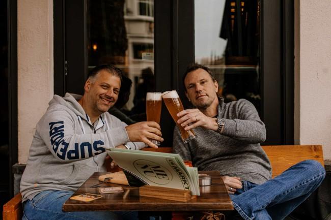 Gastrobar de Markt Breda – Twee vrienden proosten met speciaalbier op het terras