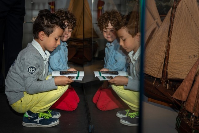 kinderen bekijken museumboekje bij scheepsmodel