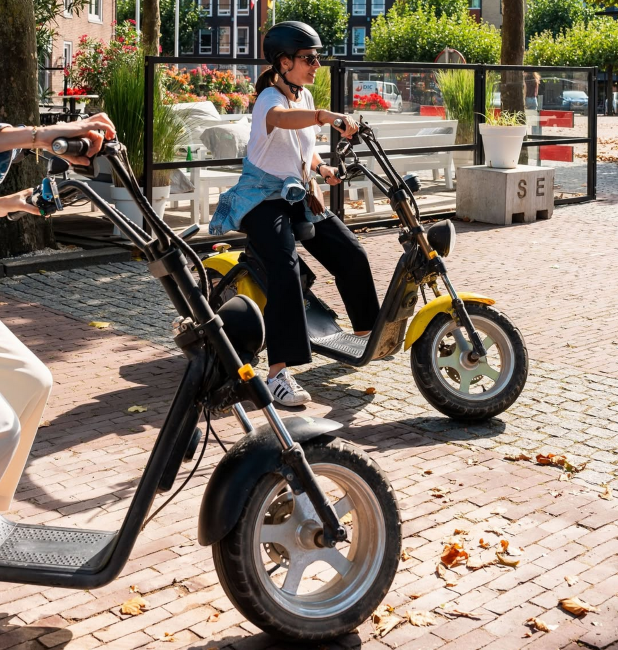 vrouw rijdt elektrische scooter door gezellige straat in zonlicht