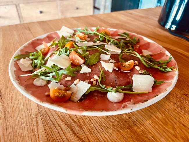 carpaccio met rucola parmezaan en tomaatjes op houten tafel