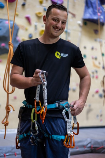 kliminstructeur bij klimcentrum yellow stone toont klimuitrusting met een glimlach