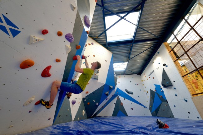 man klimt op een kleurrijke boulderwand in een moderne klimhal