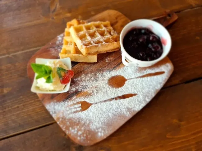 verse wafels met kersen en slagroom op houten plank