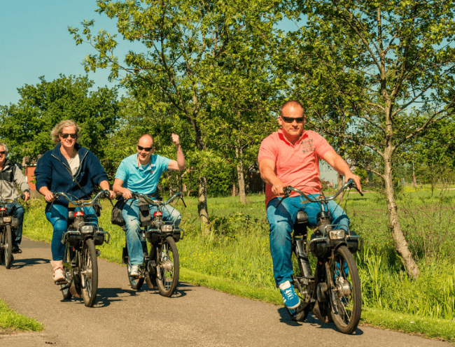 groep mensen rijdt plezierig op solexen door de natuur
