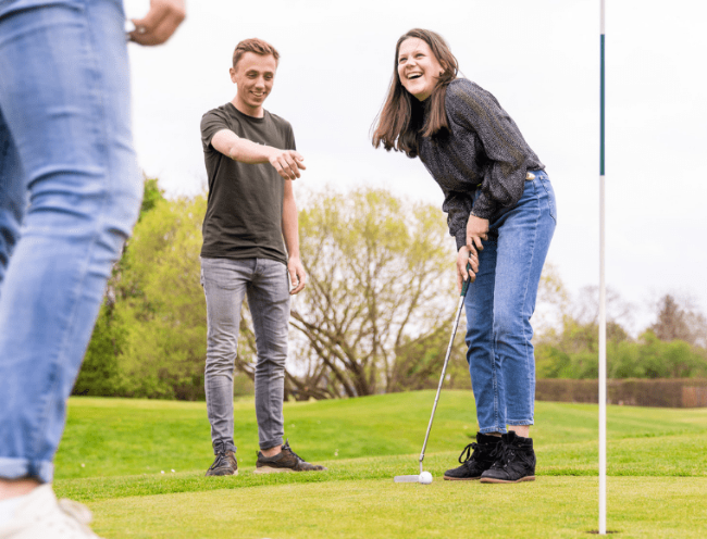 lachend team speelt pitch en putt op groene golfbaan