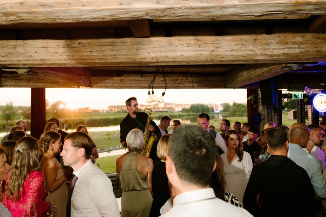 saxofonist vermaakt feestende gasten bij zonsondergang