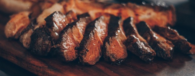 gegrild vlees in plakken op houten plank