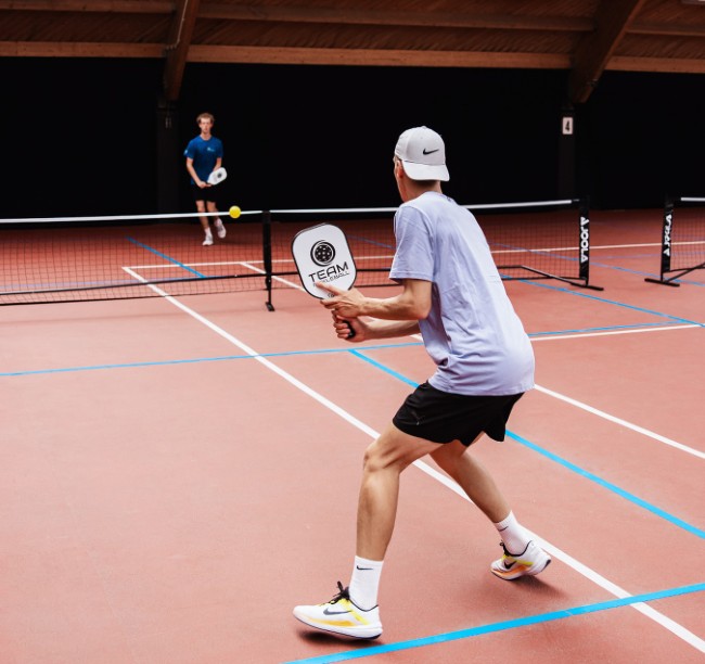 jongeren spelen pickleball op indoorbaan