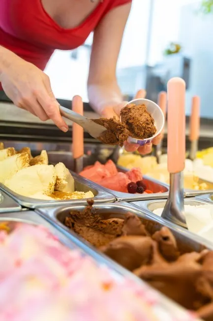 schepijs wordt vers geserveerd door medewerkster in ijssalon