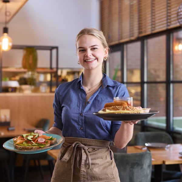 vriendelijke serveerster met lunchgerechten in brasserie t smokkelstrand chaam