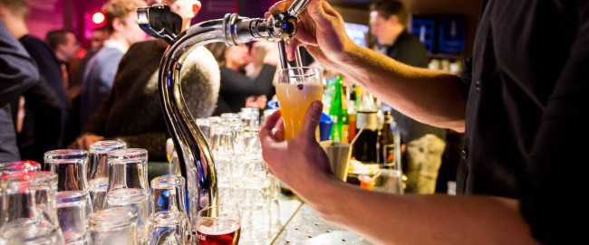 barman tapt bier aan de bar tijdens drukke avond