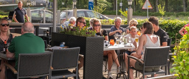 gezellig terras met gasten die samen borrelen in de zon