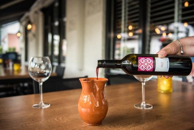 rode wijn inschenken in karaf op terras mythos