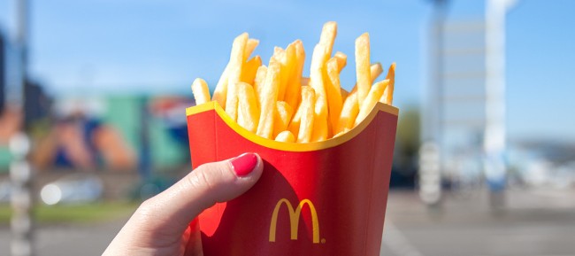 verse goudgele frietjes in mcdonalds verpakking vastgehouden in zonlicht