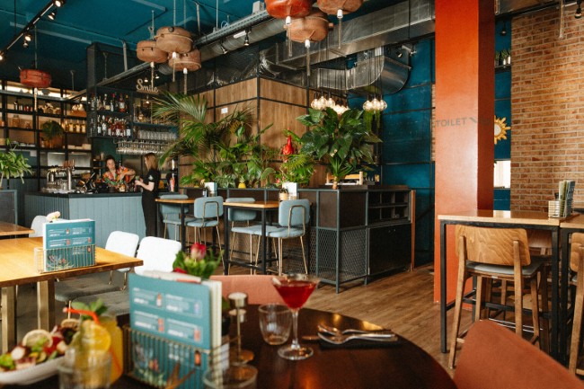 Gezellige zitplek binnen Brasserie LouLou met planten en kleurrijke accenten