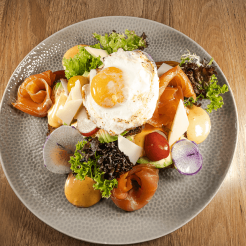 Een kleurrijke en smaakvolle salade met gerookte zalm, een spiegelei en frisse groenten, perfect voor een culinaire lunch.