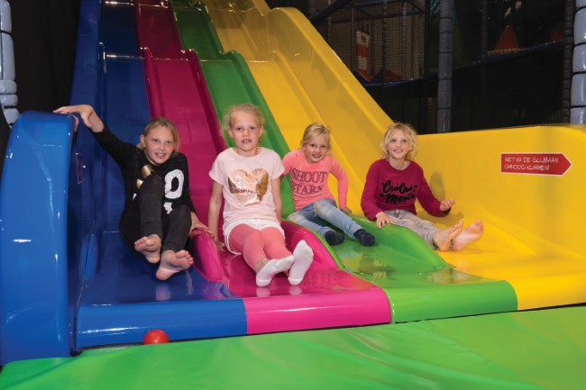 kinderen glyden van kleurryke glybanen in het speelparadys